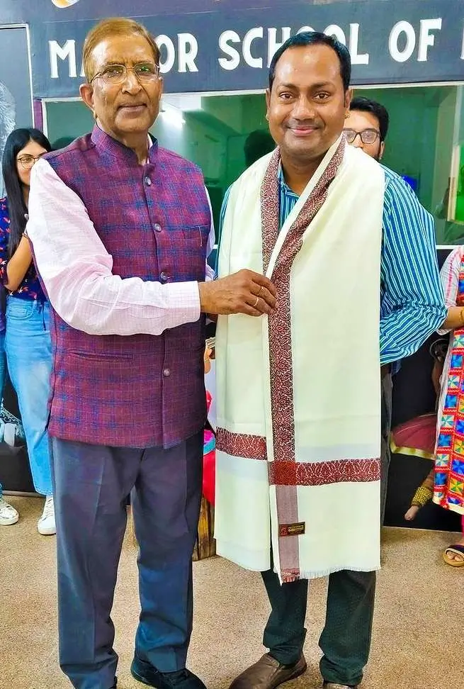 Ashish Shrivastava presenting a shawl to Mayoor Chaudhary, the founder of Mayoor School of Music, during an event.